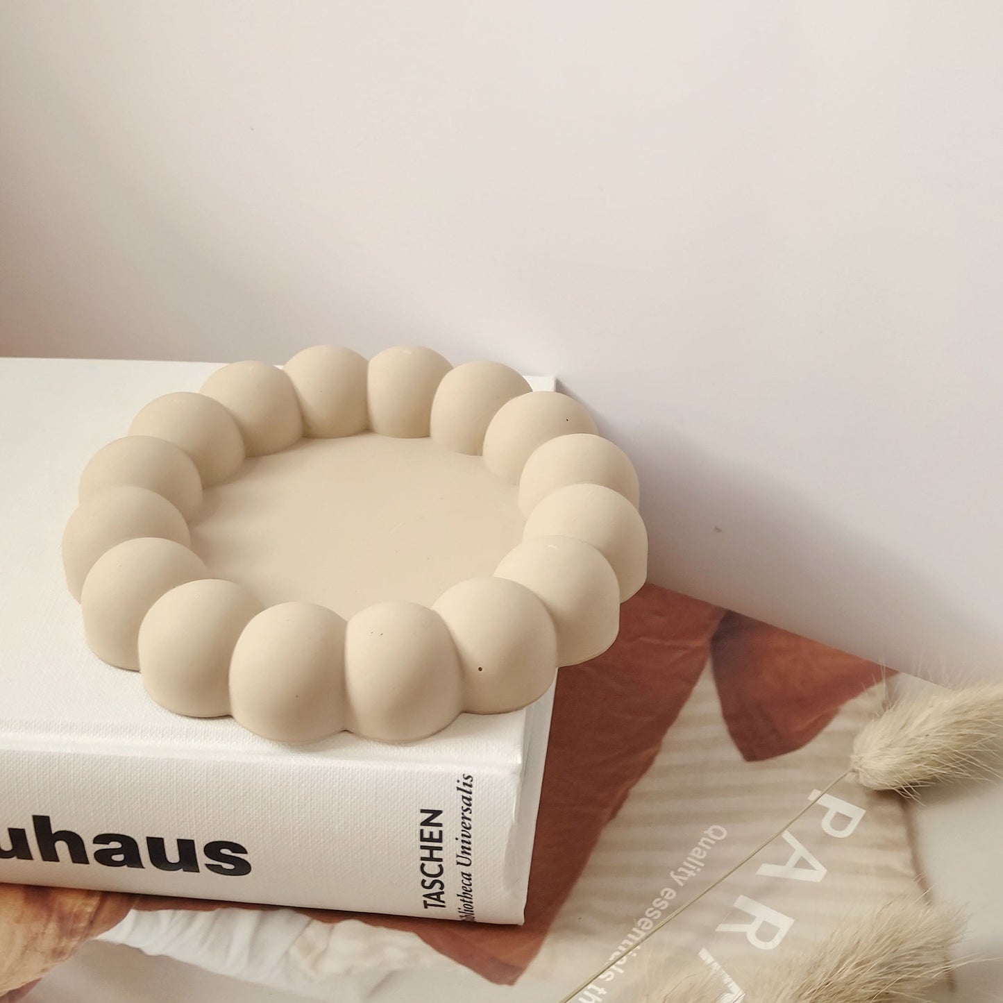 Jesmonite jewelry tray in beige color on a desk.