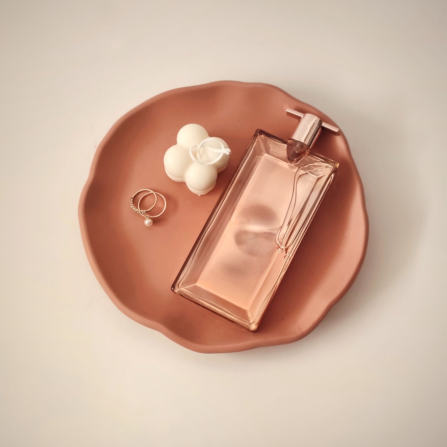 Ruffle-shaped, round jesmonite vanity tray by Kndly home in terracotta color, used as a jewelry, candle, perfume organizer.