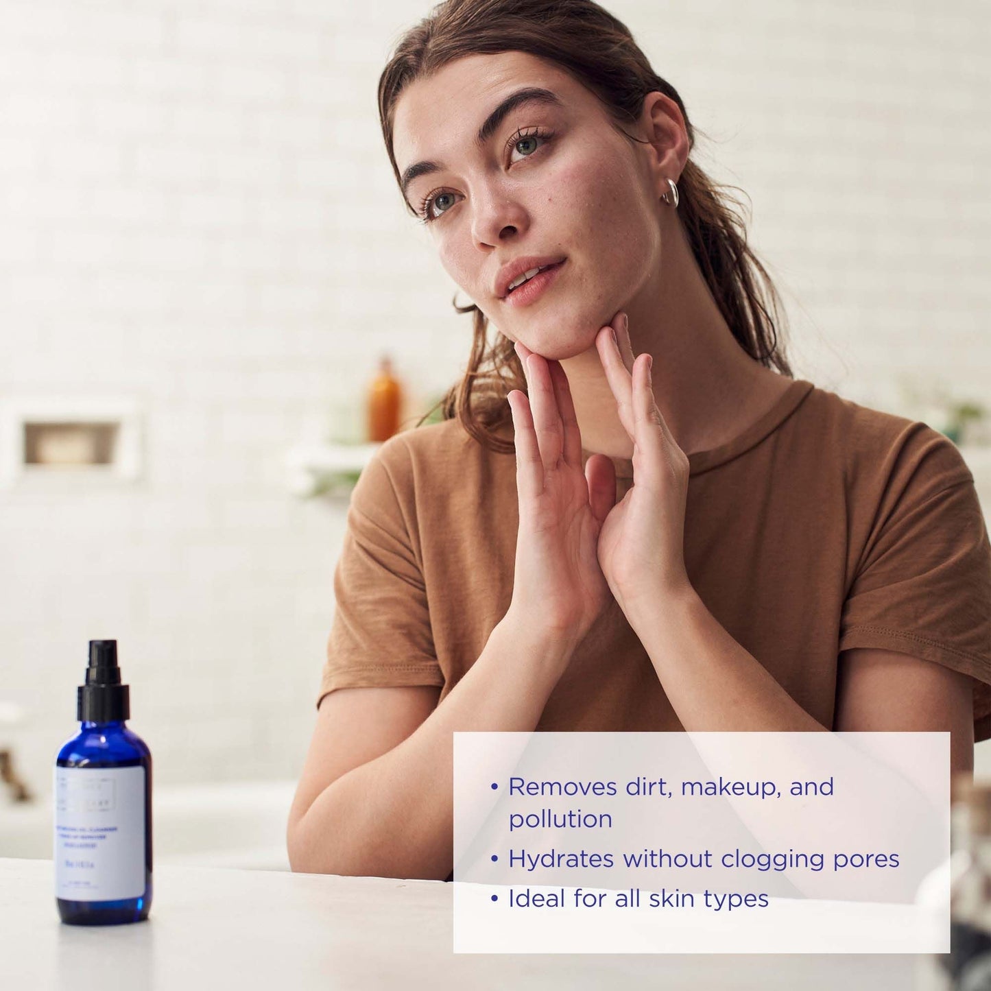 A woman applying the oil cleanser from Province Apothecary to her face, with notes indicating the cleanser removes dirt and hydrates clogged pores..