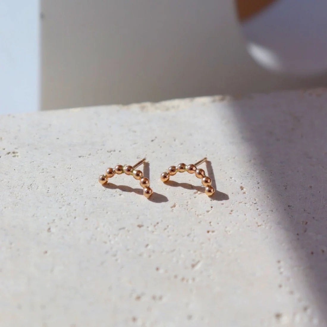 An arched stud earring in 14k yellow gold fill, by Token Jewelry.