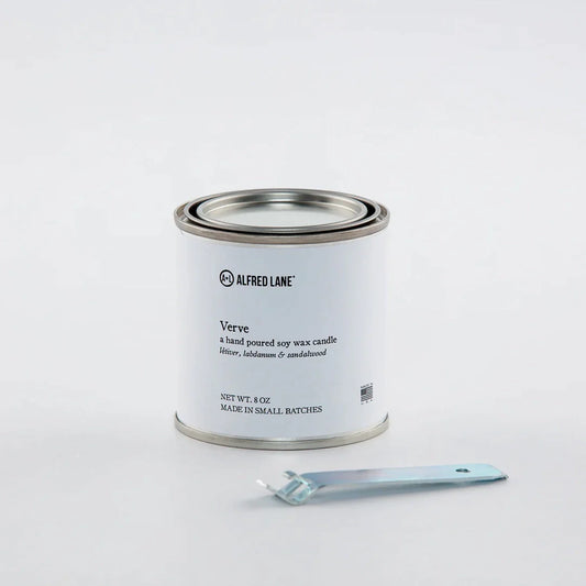 A hand-poured soy wax candle by Alfred Lane in a tin container with a tin opener.