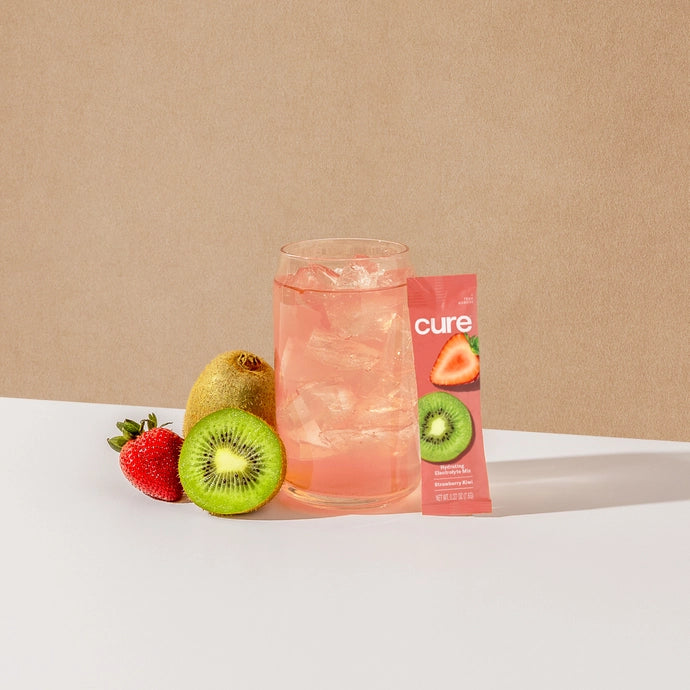 A glass of hydrating electrolyte drink mix in kiwi strawberry flavour from Cure Hydration.
