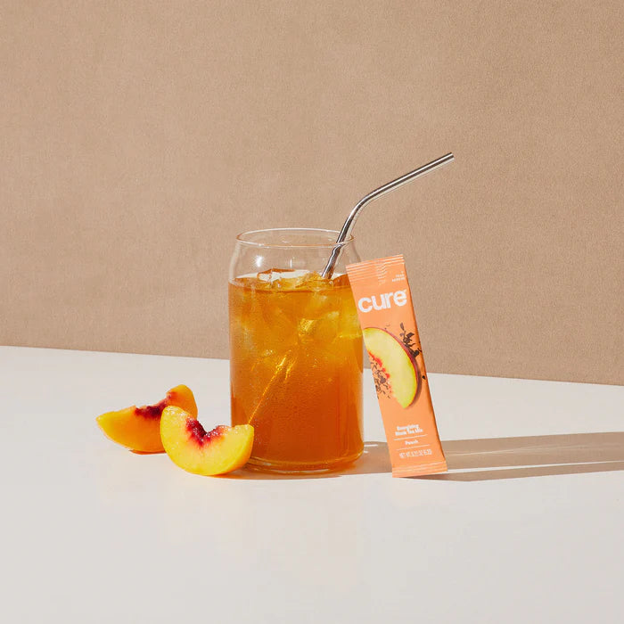 A glass of hydrating electrolyte drink mix in peach tea flavour from Cure Hydration.