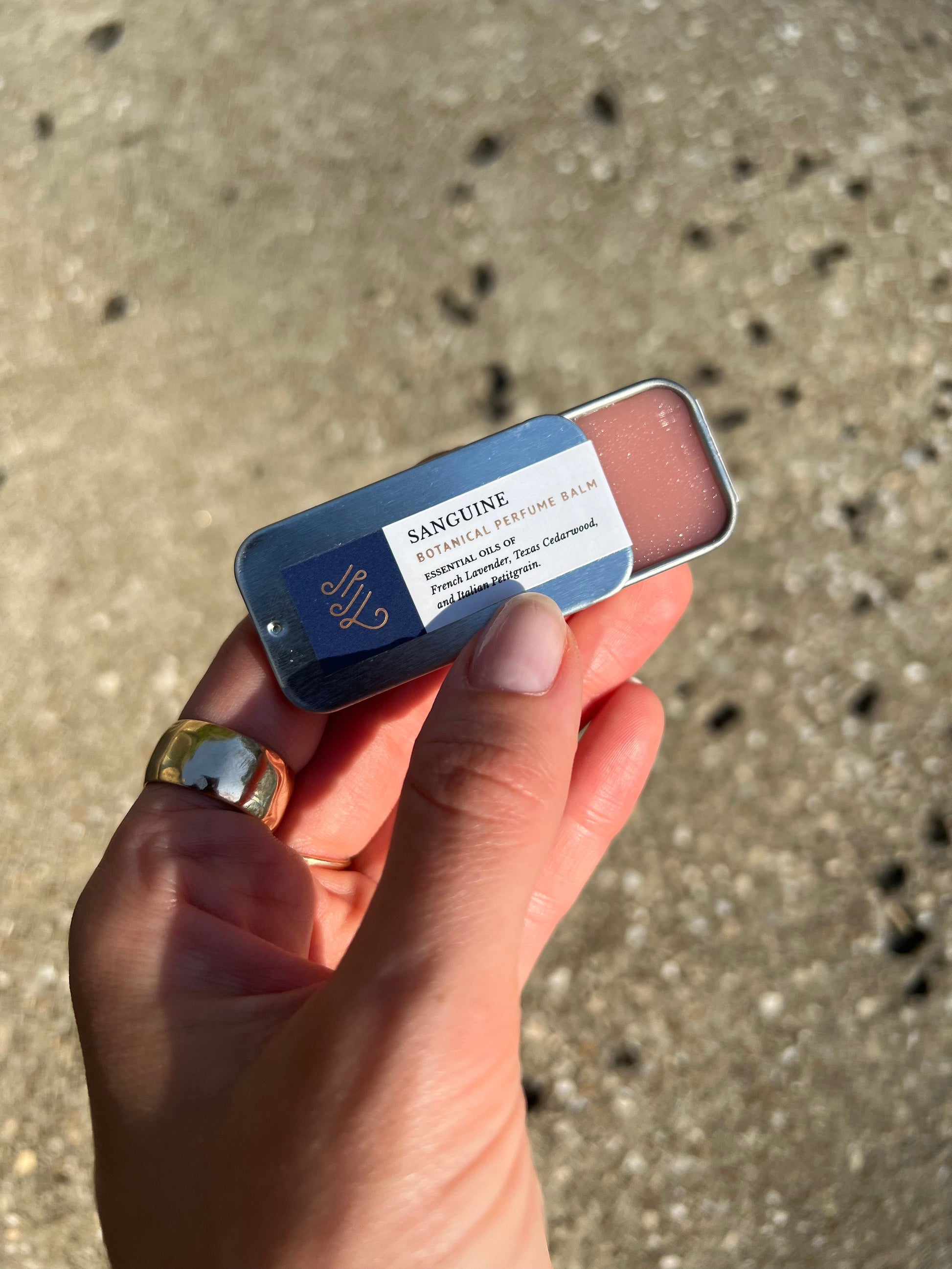 A woman holding a tin of perfume balm naturally handmade with essential oils by Even Keel.
